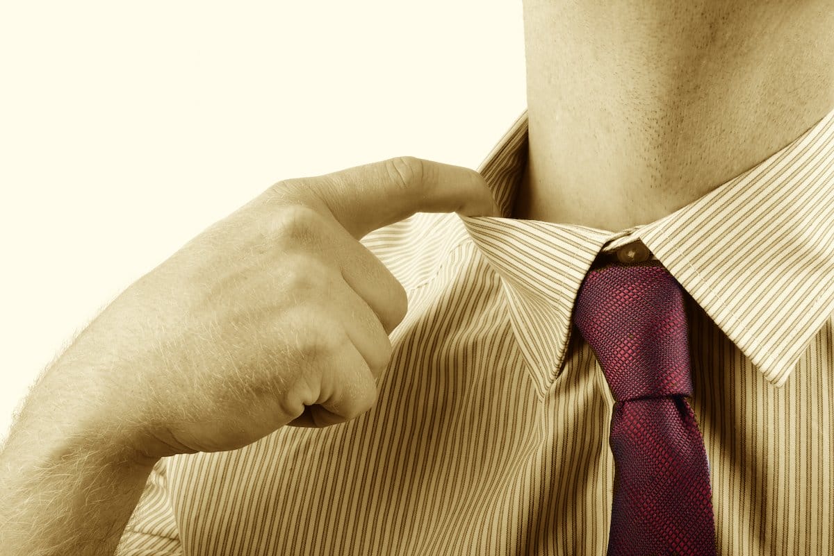 a man pulling at his shirt collar to represent how to deal with stress in the workplace