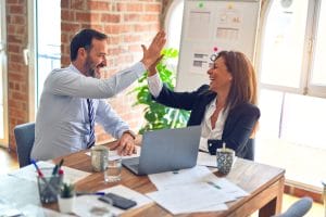 work colleagues high fiving to represent office politics when moving your career forward