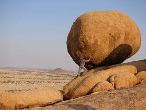 a man pushing a boulder up a hill