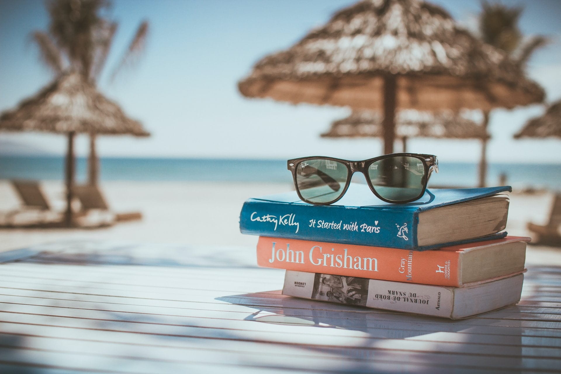 sunglasses on top of some books on the beach to represent how to switch off from work on holiday