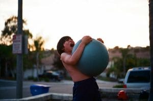 a boy squeezing a medicine ball