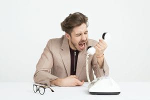 Man shouting into a phone to represent deal with difficult clients