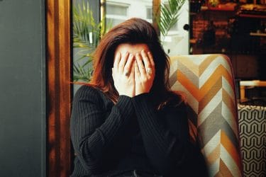 a woman covering her face with her hands to represent how to deal with difficult clients